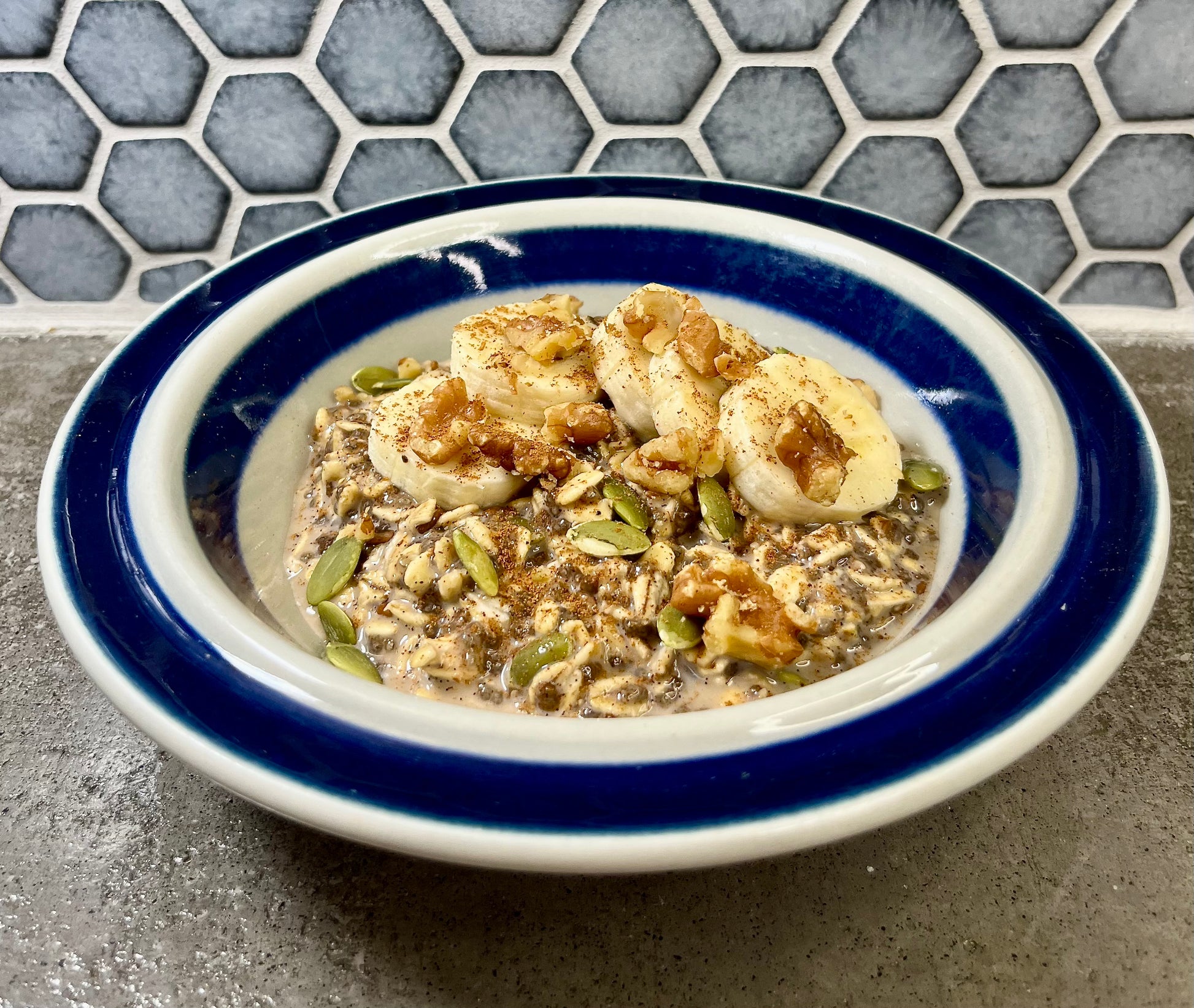 Bowl of cinnamon oatmeal with sliced bananas and walnuts.