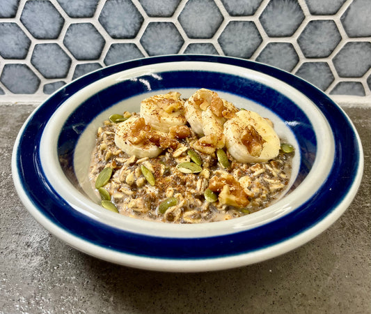 Bowl of cinnamon oatmeal with sliced bananas and walnuts.