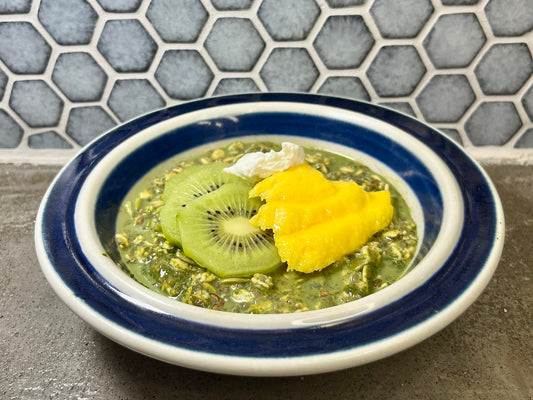 Matcha overnight oats in a bowl with mango, kiwi, and yogurt on top.